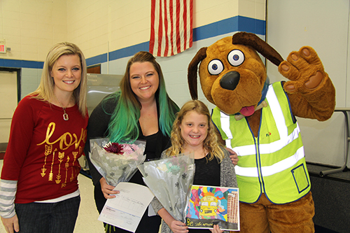 Ruth Brooks holds her winning drawing while surrounded by her teacher, principal and Safety Dog 
